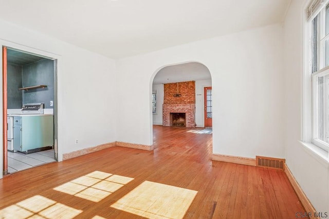 unfurnished room featuring washer / dryer, visible vents, light wood finished floors, and a wealth of natural light