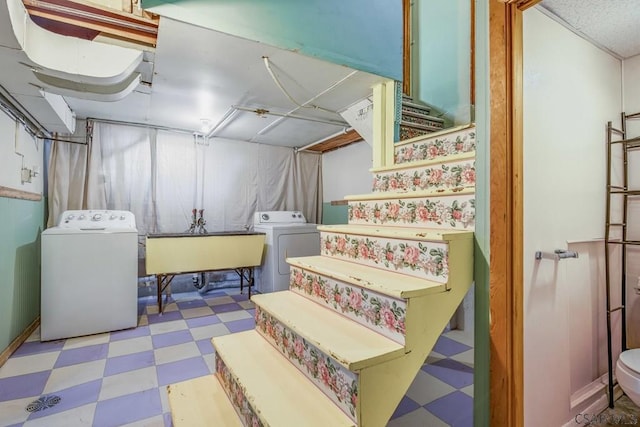 finished basement featuring stairs, washer and clothes dryer, a sink, and tile patterned floors