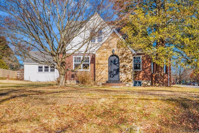 view of front of property with stone siding, fence, a front lawn, and brick siding