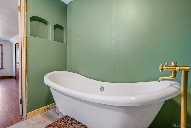 bathroom with a soaking tub and baseboards