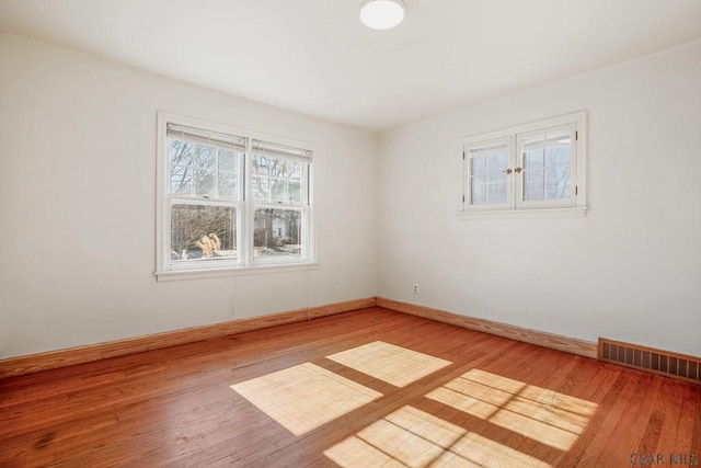 empty room featuring visible vents, baseboards, and wood finished floors