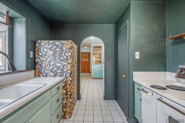 kitchen with arched walkways, light tile patterned floors, a sink, light countertops, and white range with electric stovetop