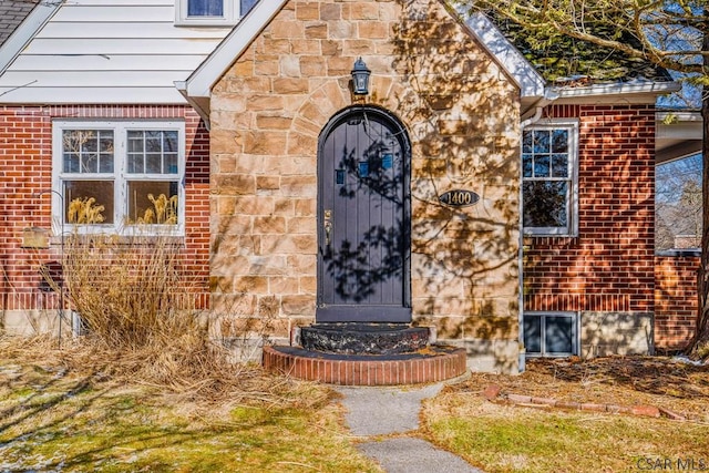 view of exterior entry with stone siding and brick siding