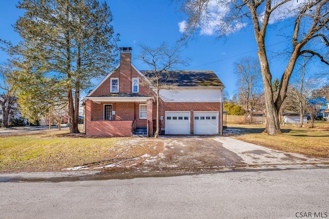 view of front of property featuring an attached garage, brick siding, driveway, a chimney, and a front yard