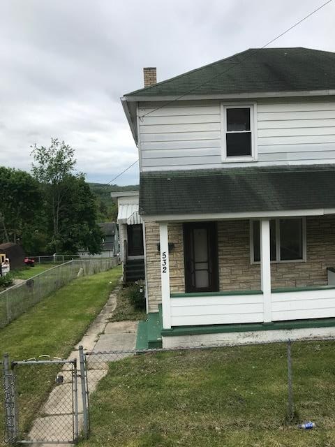 532 1st St, Windber, PA 15963 - view of front facade featuring stone siding, a chimney, roof with shingles, and a gate