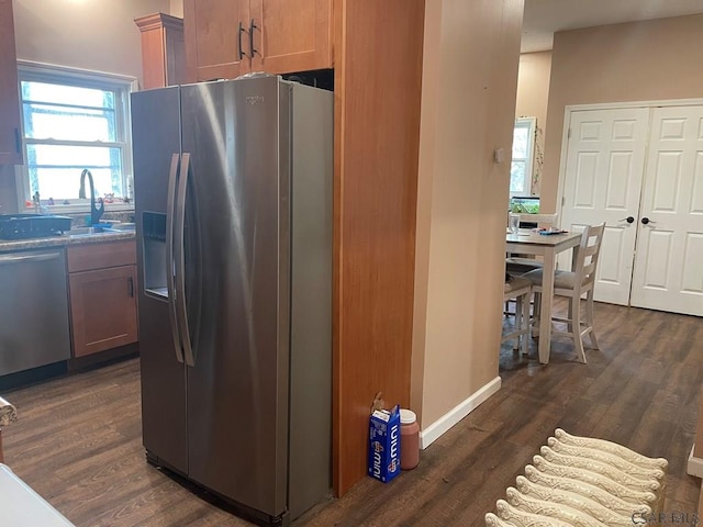 kitchen featuring a sink, stainless steel appliances, baseboards, and dark wood-style flooring