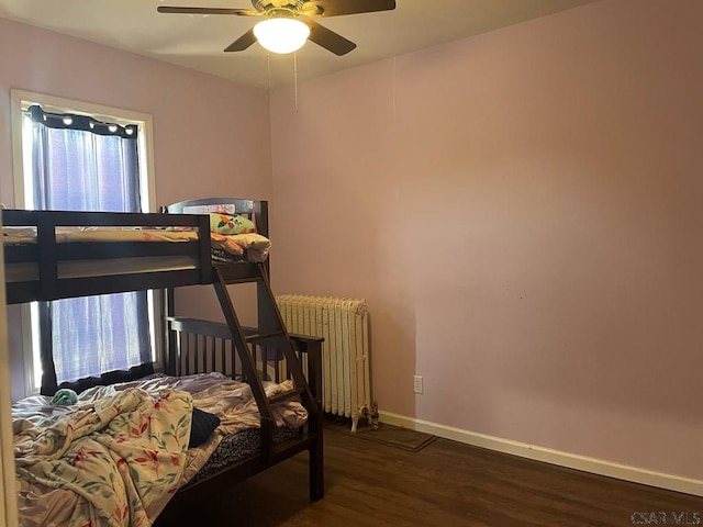 bedroom with a ceiling fan, radiator heating unit, baseboards, and wood finished floors