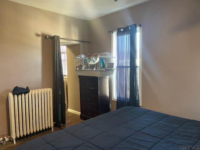 bedroom with radiator and wood finished floors