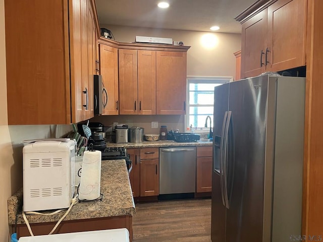 kitchen featuring dark wood-type flooring, light stone counters, recessed lighting, brown cabinetry, and stainless steel appliances