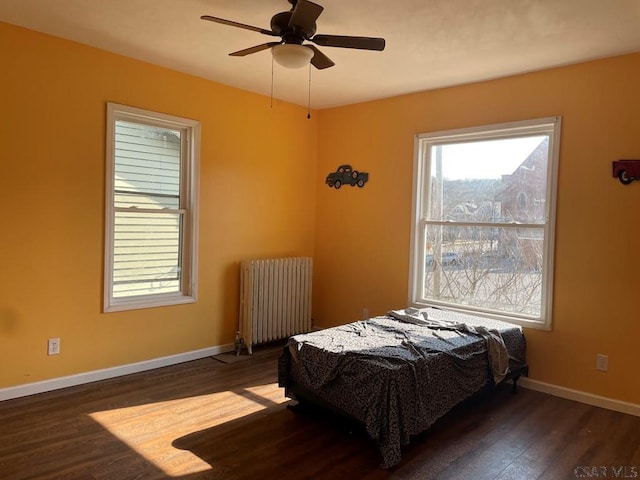 bedroom featuring ceiling fan, baseboards, wood finished floors, and radiator heating unit