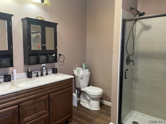 bathroom with a shower stall, baseboards, toilet, wood finished floors, and vanity