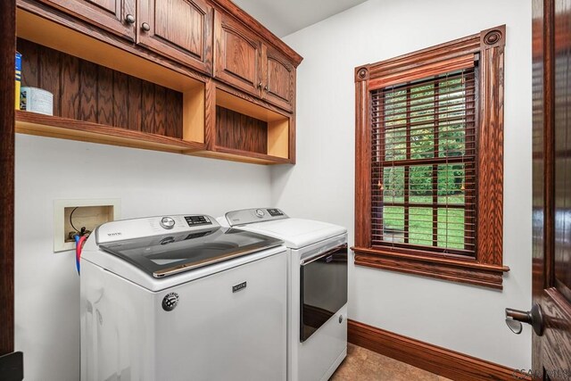 washroom featuring cabinets, light tile patterned floors, and washer and dryer