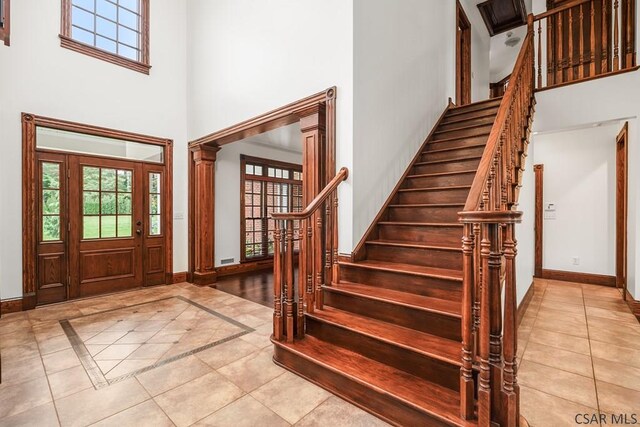 tiled foyer with decorative columns and a high ceiling