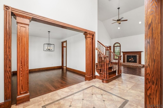 interior space with ornate columns, lofted ceiling, light tile patterned floors, and a chandelier