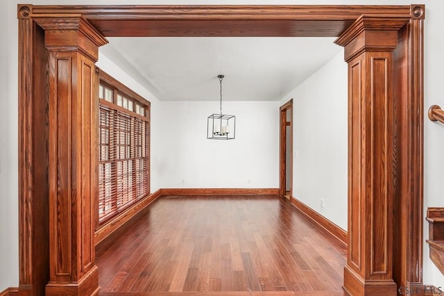 unfurnished dining area featuring dark hardwood / wood-style floors and ornate columns