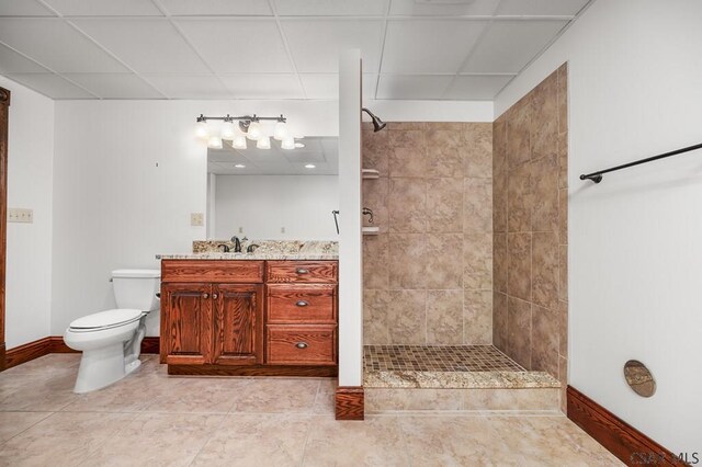 bathroom with a tile shower, vanity, a paneled ceiling, and toilet