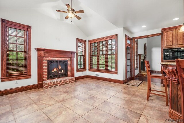 unfurnished living room with a fireplace, a wealth of natural light, vaulted ceiling, and light tile patterned flooring