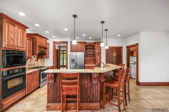 kitchen with a center island with sink, light tile patterned floors, pendant lighting, stainless steel appliances, and light stone countertops