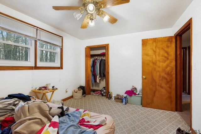 bedroom featuring ceiling fan, light carpet, and a closet