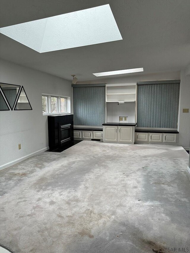 unfurnished living room featuring carpet floors and a skylight