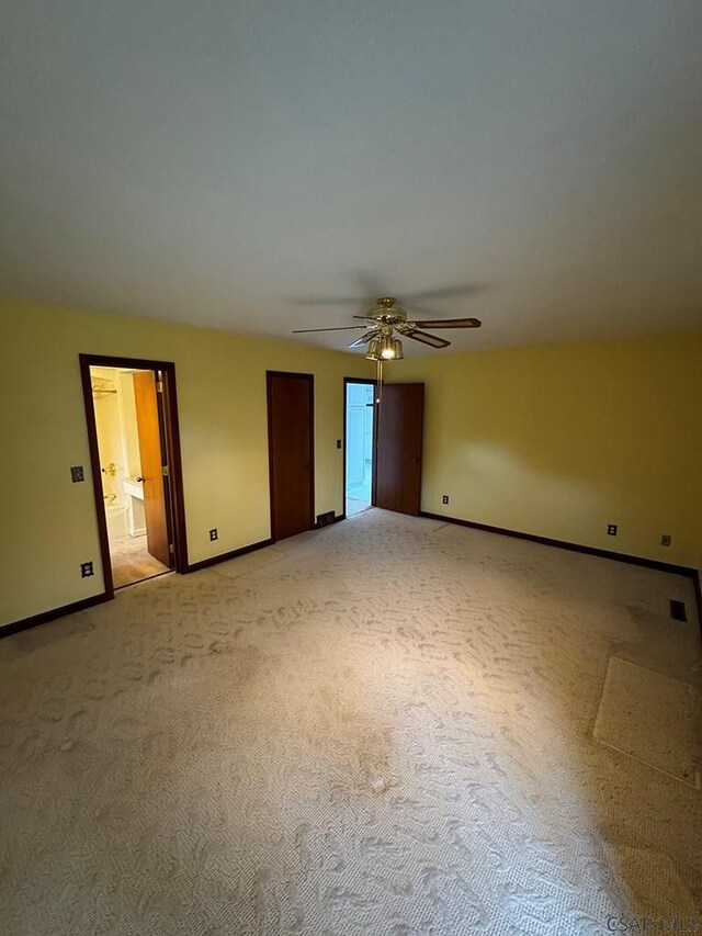 unfurnished bedroom featuring light carpet, connected bathroom, and ceiling fan