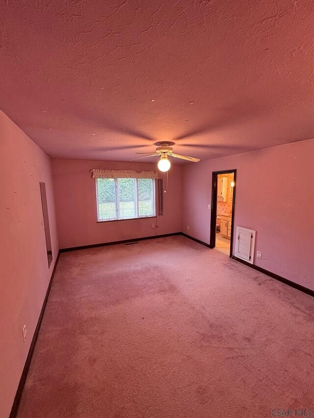 carpeted spare room featuring ceiling fan and a textured ceiling