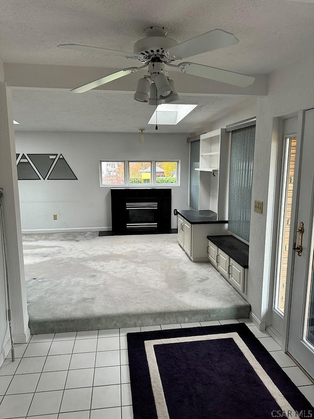 interior space with white cabinets, light tile patterned floors, ceiling fan, a textured ceiling, and built in shelves