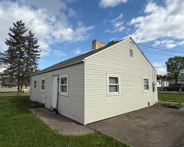 view of property exterior with a yard, a patio, and a chimney
