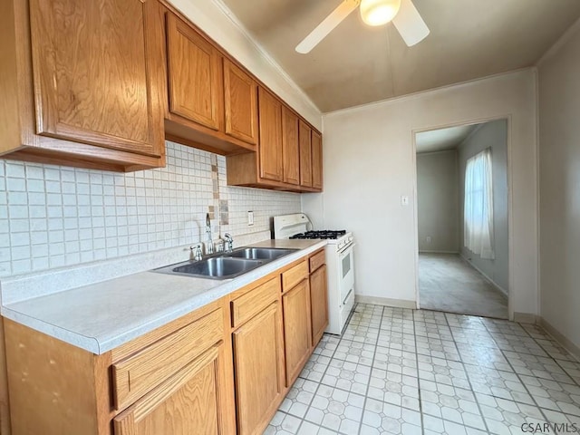 kitchen with ceiling fan, a sink, white gas stove, backsplash, and light countertops