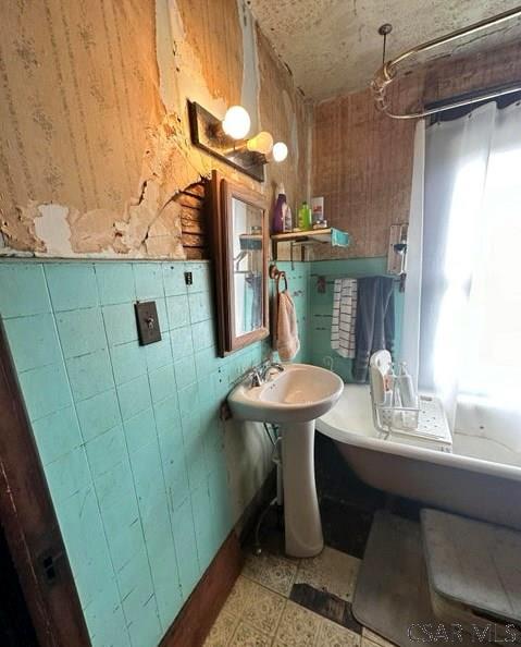 bathroom featuring shower / bath combo, sink, and wood walls