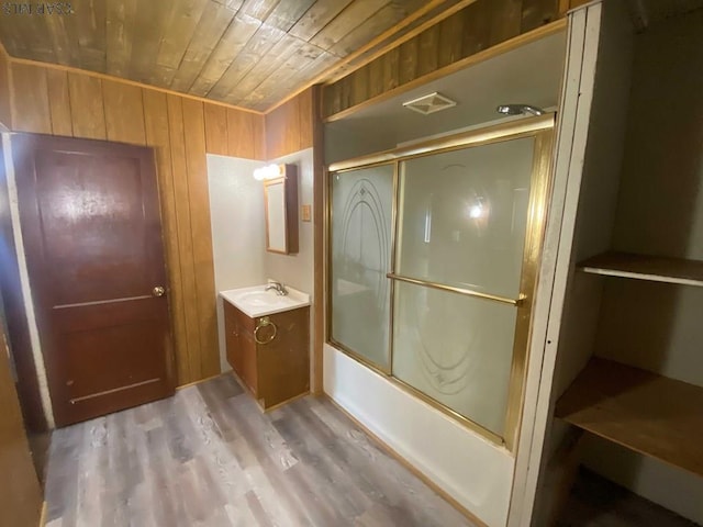 bathroom featuring visible vents, shower / bath combination with glass door, wood walls, wooden ceiling, and vanity