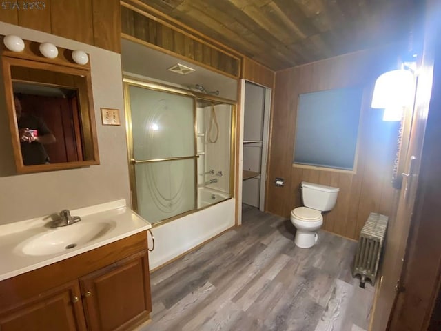 full bathroom with vanity, wood finished floors, radiator heating unit, toilet, and combined bath / shower with glass door