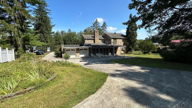 view of front facade featuring an attached garage, fence, concrete driveway, a front lawn, and a chimney