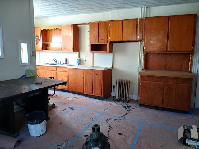 kitchen featuring radiator, sink, and a textured ceiling