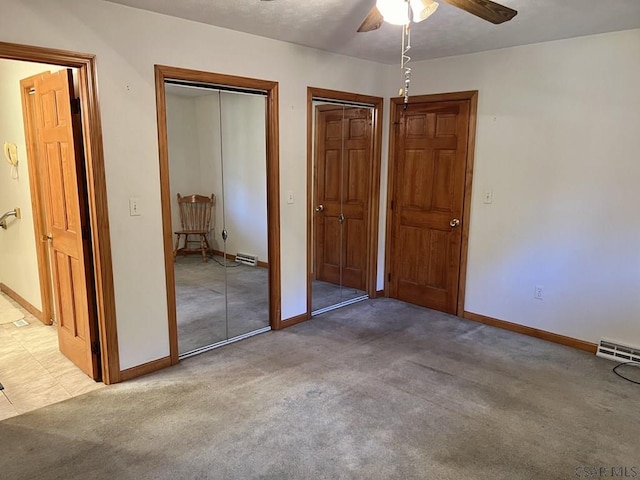 unfurnished bedroom featuring carpet flooring, two closets, and ceiling fan