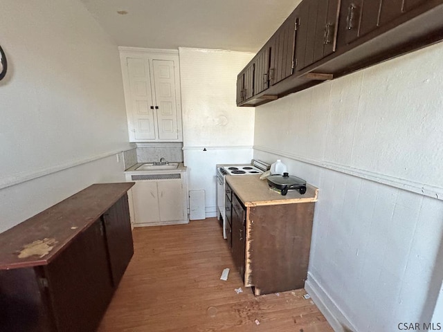 kitchen with light wood-type flooring, dark brown cabinetry, sink, and white range with electric stovetop