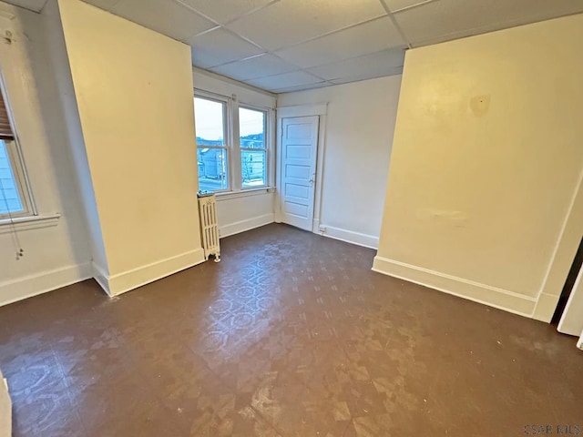 spare room with radiator and a paneled ceiling