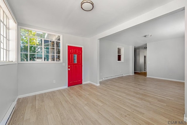 unfurnished room with a baseboard heating unit and light hardwood / wood-style floors