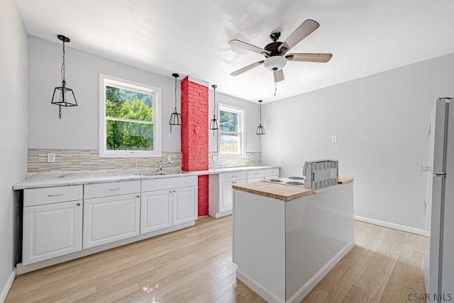 kitchen featuring white cabinetry, white refrigerator, and decorative light fixtures