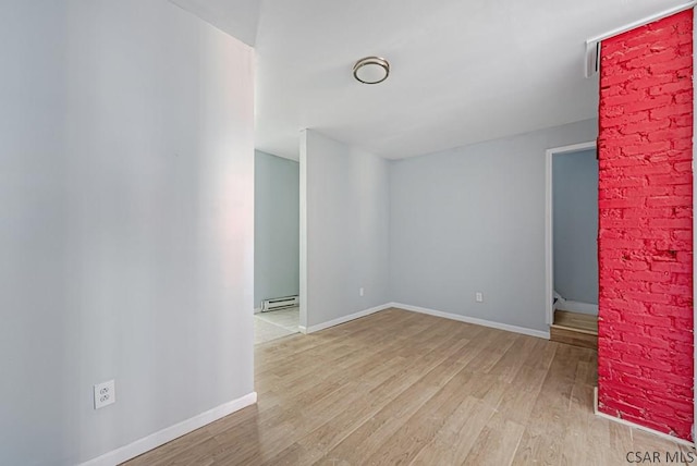 unfurnished room featuring baseboard heating and light hardwood / wood-style flooring