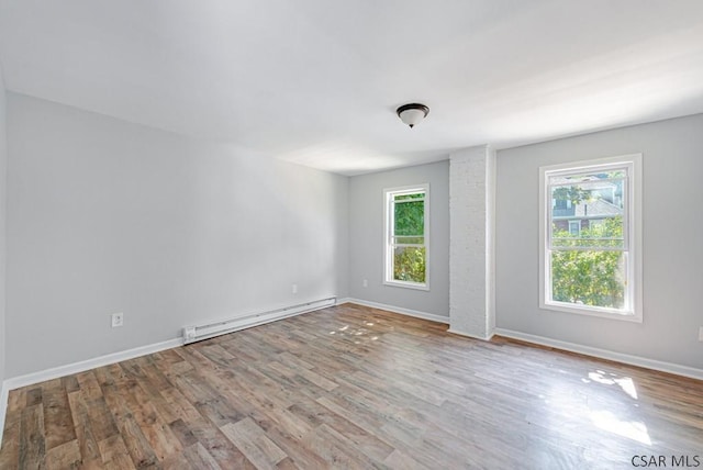 unfurnished room featuring a wealth of natural light, light hardwood / wood-style flooring, and a baseboard heating unit