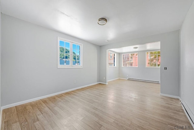 spare room featuring a baseboard heating unit and light hardwood / wood-style floors