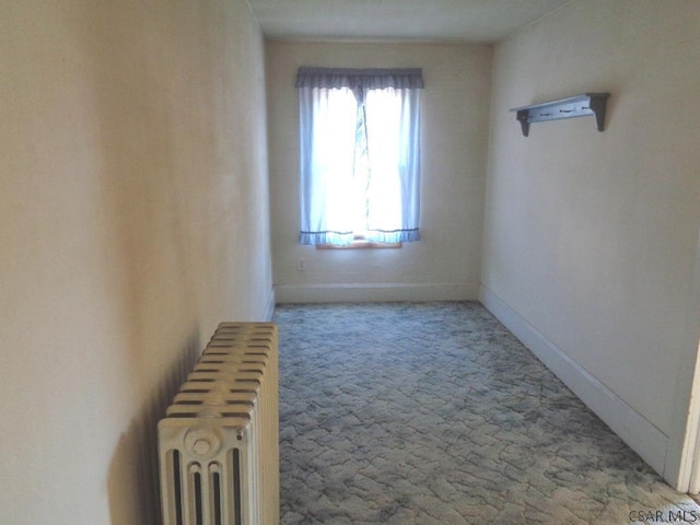 unfurnished room featuring baseboards, radiator, and carpet flooring