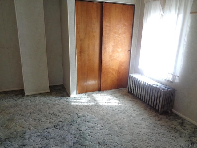 unfurnished bedroom with radiator heating unit, baseboards, and carpet floors