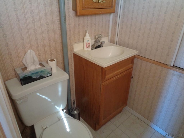 half bathroom featuring tile patterned floors, toilet, vanity, and wallpapered walls