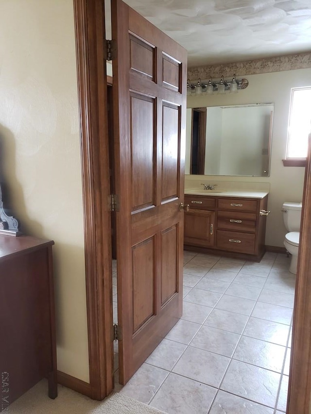 bathroom with baseboards, vanity, toilet, and tile patterned floors