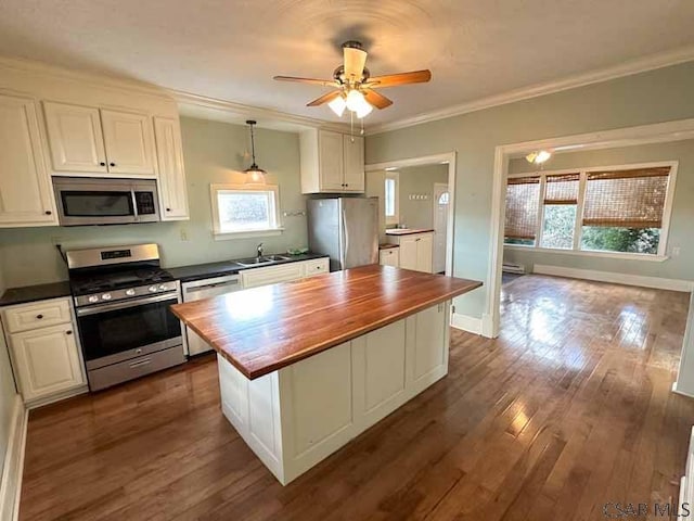 kitchen with sink, white cabinetry, butcher block counters, stainless steel appliances, and a center island