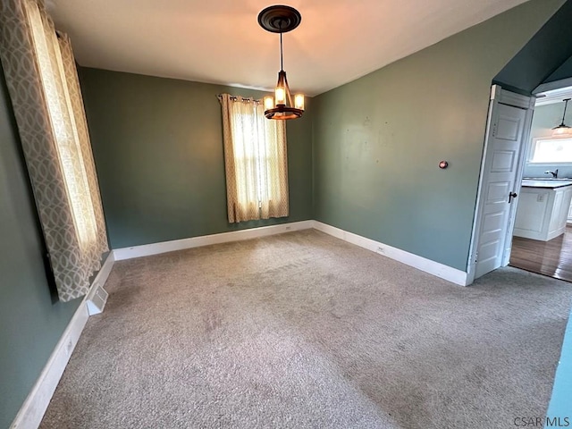 carpeted spare room featuring an inviting chandelier, sink, and a wealth of natural light