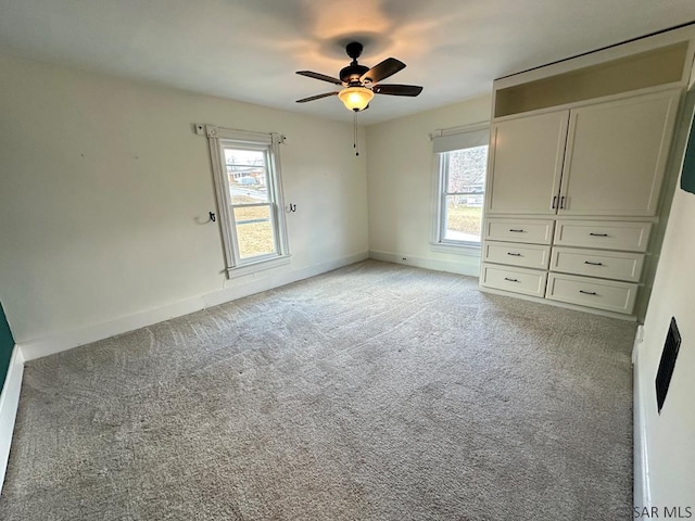 unfurnished bedroom with multiple windows, light colored carpet, and ceiling fan