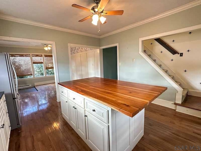 kitchen featuring dark wood-type flooring, butcher block counters, stainless steel refrigerator, ornamental molding, and white cabinets